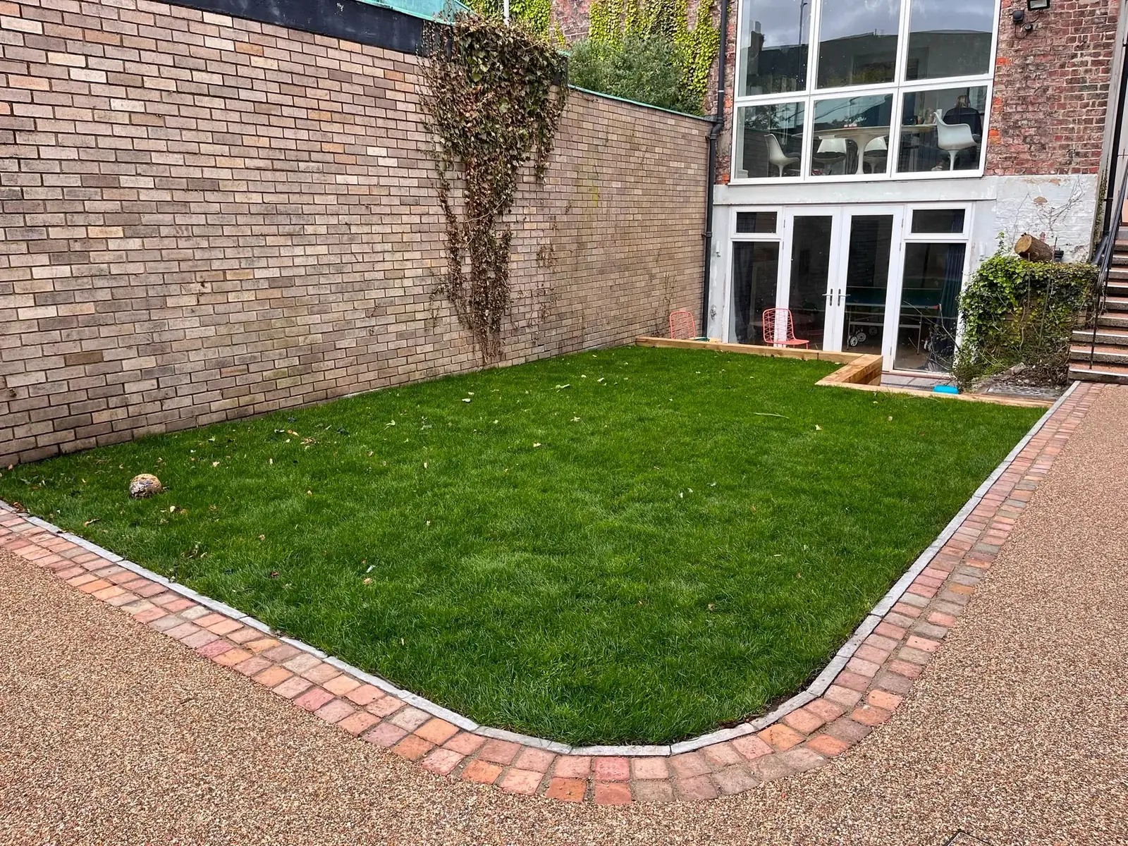 Finished rear garden in Newcastle with a fresh lawn bordered by brick edging and golden resin surfacing